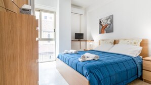 Une chambre à coucher avec un lit, une télévision, un tableau et une fenêtre.