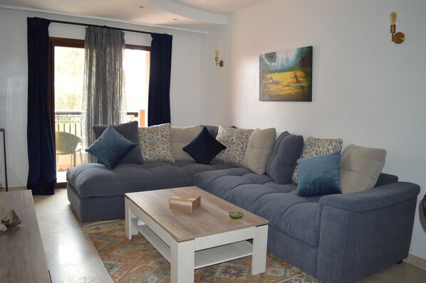 A living room with a grey sectional sofa, a wooden coffee table, and a painting on the wall.
