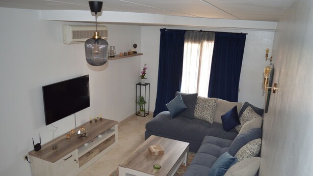 A modern living room with a flat-screen TV, a wooden coffee table, a grey sofa with patterned cushions, and a decorative plant. - Appart Chic EL Pacha hypercentre Gueliz station (Marrakech)