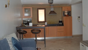 A compact kitchen with a central island, a built-in oven, and a microwave. There are two bar stools and a coffee machine on the counter. - Appart Chic EL Pacha hypercentre Gueliz station (Marrakech)