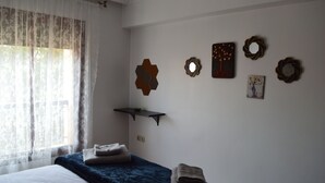 A bedroom with a bed, a window with sheer curtains, and wall decorations including hexagonal mirrors and a framed picture. - Appart Chic EL Pacha hypercentre Gueliz station (Marrakech)