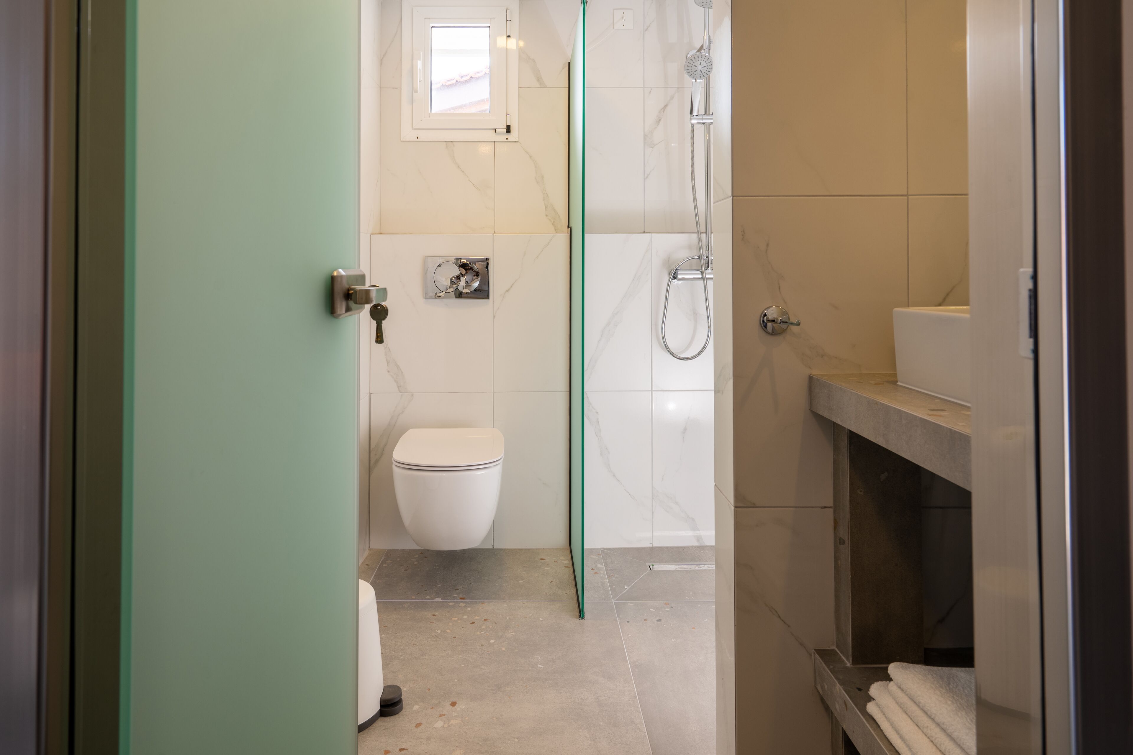 Un baño moderno con inodoro, ducha y mampara de vidrio.