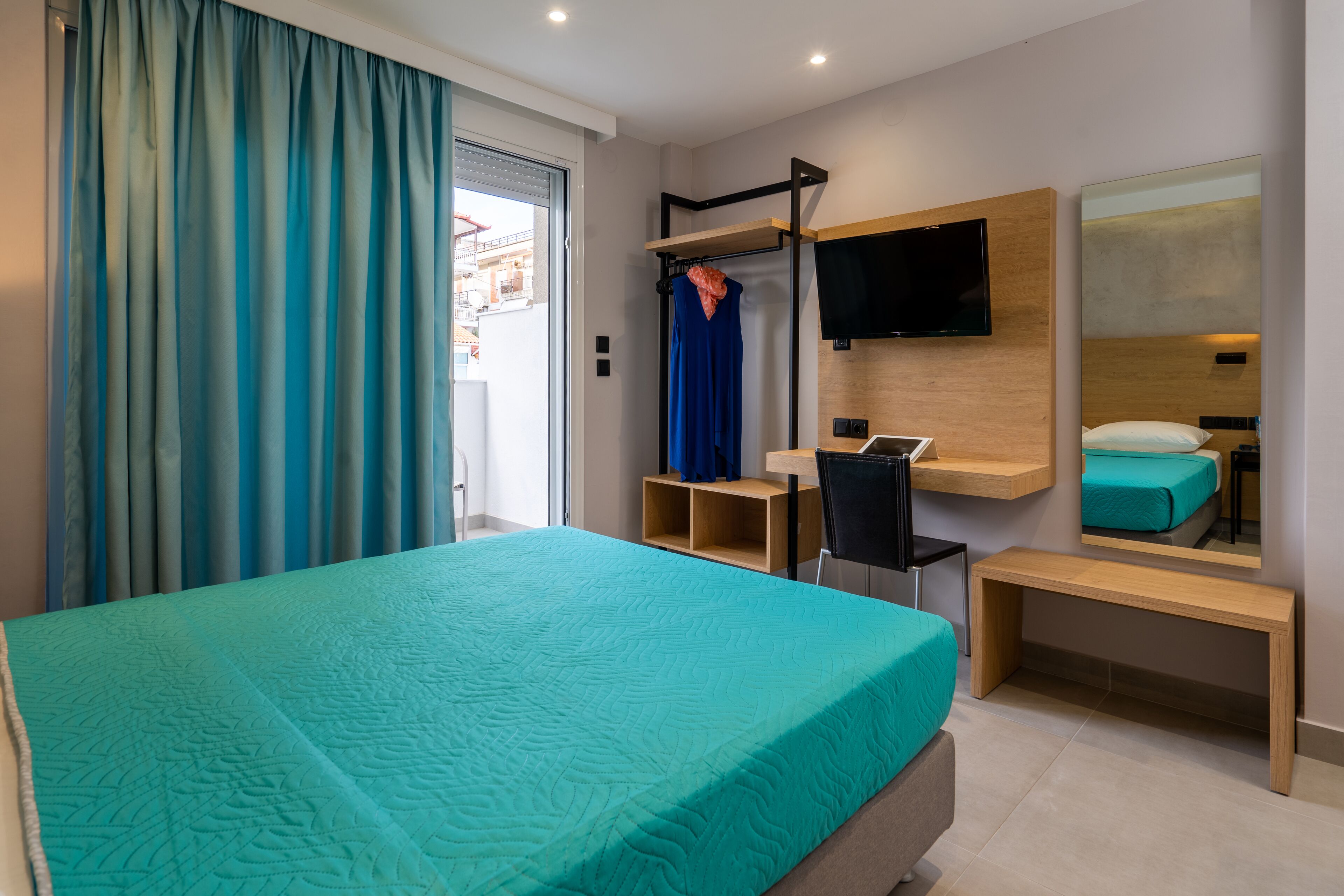 Ein modernes Hotelzimmer mit einem großen Bett, einem Schreibtisch, einem Sessel, einem Fernseher und einem Spiegel.