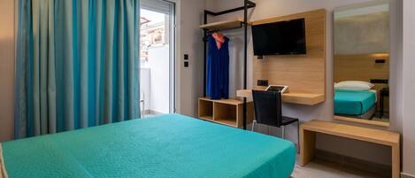 Ein modernes Hotelzimmer mit einem großen Bett, einem Schreibtisch, einem Sessel, einem Fernseher und einem Spiegel.