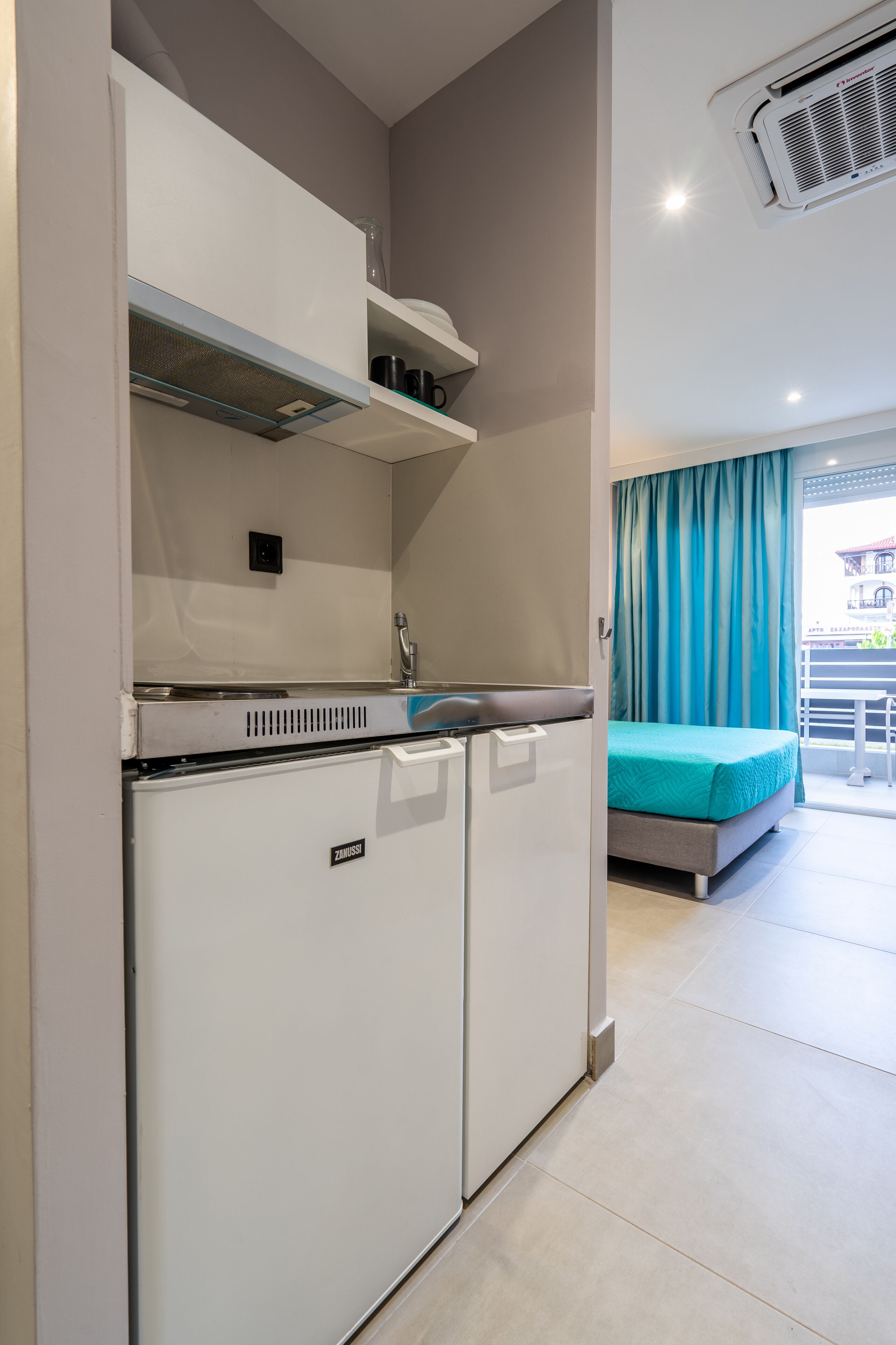 Una kitchenette compacta con refrigerador, estufa y lavamanos.