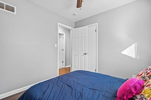 A bedroom with a bed, a door, and a window. - Boho Lounge - Pet Friendly Home Close to I-35 & KC (Merriam)