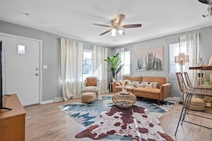 A living room with a ceiling fan, a sofa, a coffee table, and a rug. - Boho Lounge - Pet Friendly Home Close to I-35 & KC (Merriam)