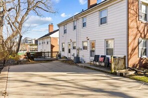 A residential street with two-story houses, a sidewalk, and a wooden fence.