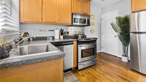 A modern kitchen with wooden cabinets, stainless steel appliances, and a granite countertop. - Kansas City Townhouse Walk to Plaza+Streetcar 1006 (Kansas City)