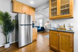 A modern kitchen with wooden cabinets, a stainless steel refrigerator, and a potted plant.
