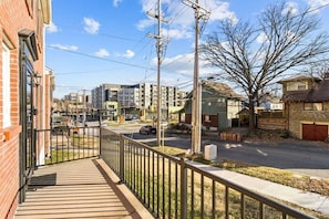 A residential street with a brick building, a metal fence, and a clear sky.