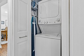 A laundry room with a washing machine and dryer, a door, and a hanging rack.