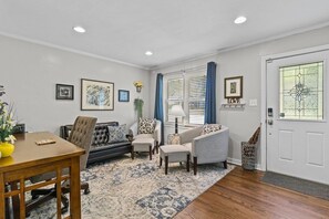 A living room with a sofa, armchairs, a coffee table, and a dining table. - Jefferson St. Cottage - Large Home w/ Fenced Yard (Kansas City)