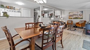 A modern kitchen with white cabinetry, a dining table with chairs, and a cityscape painting on the wall.