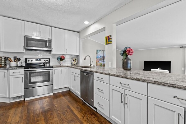 A modern kitchen with white cabinets, stainless steel appliances, and a granite countertop.