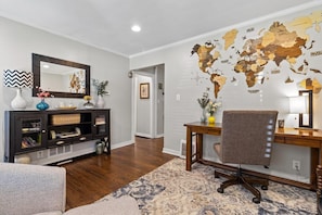 Una sala de estar con un mapa mundial en la pared, un escritorio de madera, una silla y un sofá.