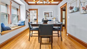 Comedor con mesa y sillas de madera, un candelabro y un ventanal con vistas.