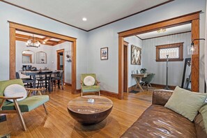 A spacious living area with a wooden dining table, a round coffee table, and a leather sofa. - KC Nest - Walkable to Plaza + Parking + Streetcar (Kansas City)