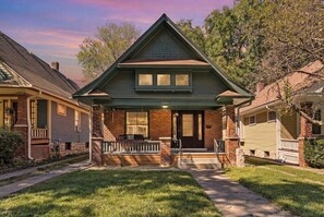 A two-story house with a front porch, brick exterior, and a visible address number. - KC Nest - Walkable to Plaza + Parking + Streetcar (Kansas City)