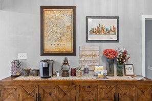 Kitchen area with a coffee maker, vase, and framed artworks.
