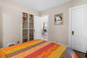 A bedroom with a large bed, a bookshelf, a door, and a framed picture on the wall. - Plaza Perch -Walk to Plaza & Westport! (Kansas City)