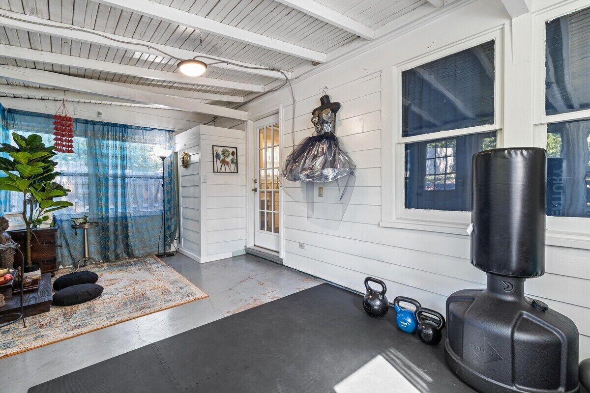 A room with a large window, a punching bag, kettlebells, and a plant.