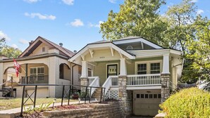 A two-story house with a garage, a front porch, and a small front yard with a retaining wall and steps. - Plaza Perch -Walk to Plaza & Westport! (Kansas City)