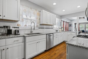A modern kitchen with white cabinetry, a granite countertop, and a stainless steel dishwasher.