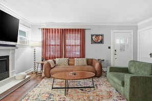 A living room with a sofa, a coffee table, a television, and a fireplace. - Plaza Perch -Walk to Plaza & Westport! (Kansas City)