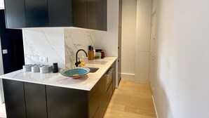 Een moderne keuken met donkere kastjes, een marmeren aanrechtblad en een inbouwoven.