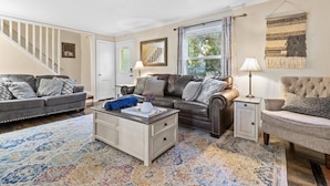 A living room with a sofa, armchair, coffee table, and a patterned rug. - Cottage Mins From Stadiums + Parking + Pet Welcome (Independence)