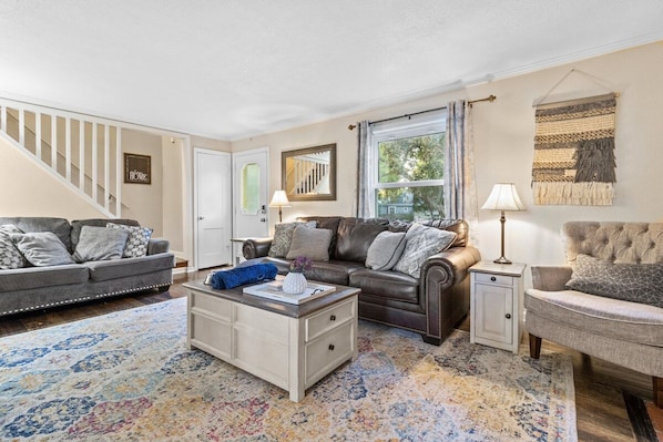 A living room with a sofa, armchair, coffee table, and a patterned rug.