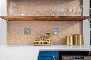Una cocina con un estante de madera que sostiene cristalería y un armario azul debajo.