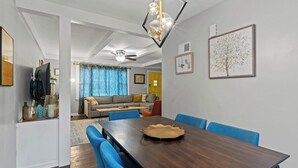 Un comedor con mesa de madera oscura, sillas azules y una araña.