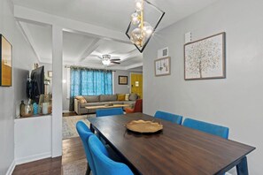 Zona pranzo con tavolo in legno scuro, sedie blu e lampadario.
