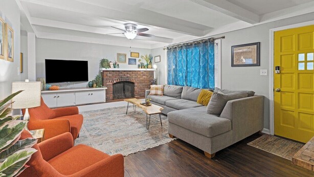 Una sala de estar con chimenea, sofá, televisor y una puerta amarilla.