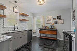 A kitchen with a black hexagonal floor, a wooden countertop, and a built-in oven.