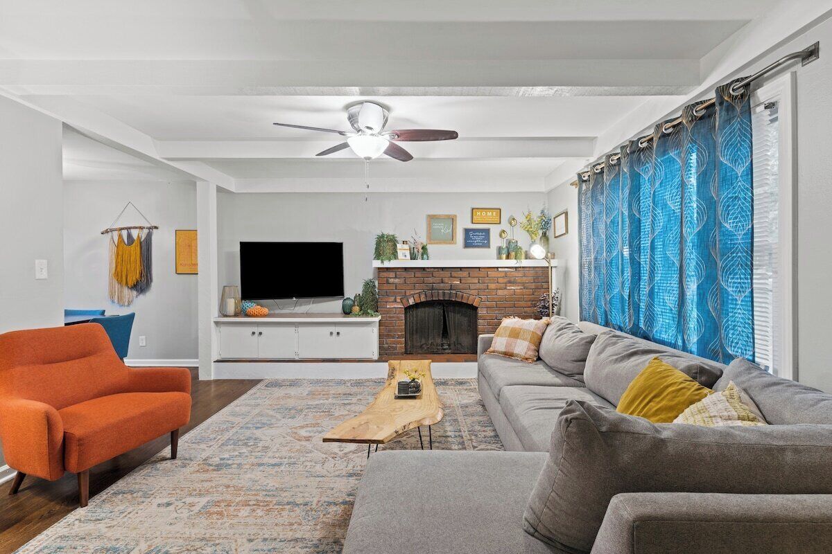 Un salon avec une cheminée, un canapé, un téléviseur et un ventilateur de plafond.
