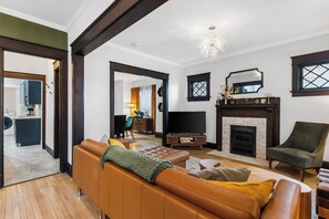 Een woonkamer met een bank, fauteuil en open haard.