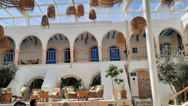 Un patio amplio con múltiples arcos, lámparas colgantes de mimbre y zonas de estar al aire libre.
