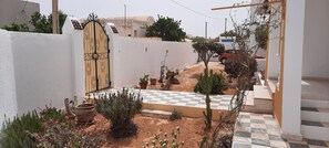 A courtyard with a checkered floor, a gate, and various potted plants. - Dar El Janna 26 - the house of paradise (Hachene)