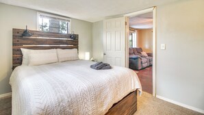 A bedroom with a large bed, a wooden headboard, a window, and a door leading to a living area. - Half-Mi to Marina: Pet-Friendly Disney Home (Disney)