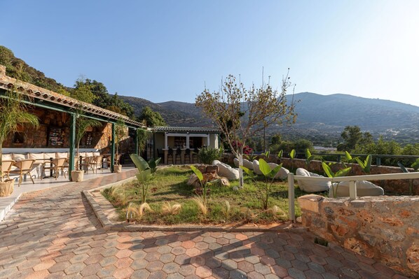 A patio area with hexagonal paving, outdoor seating, and a view of mountains in the background. - Sunny Hill by Estia (Hersonissos)