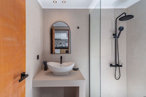 Une salle de bain moderne avec un lavabo sur pied, un miroir et une douche.