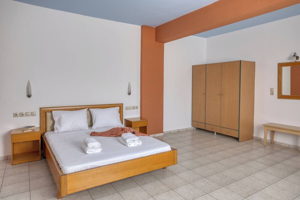 Une chambre à coucher avec un lit en bois, une armoire, une table de chevet et un banc.