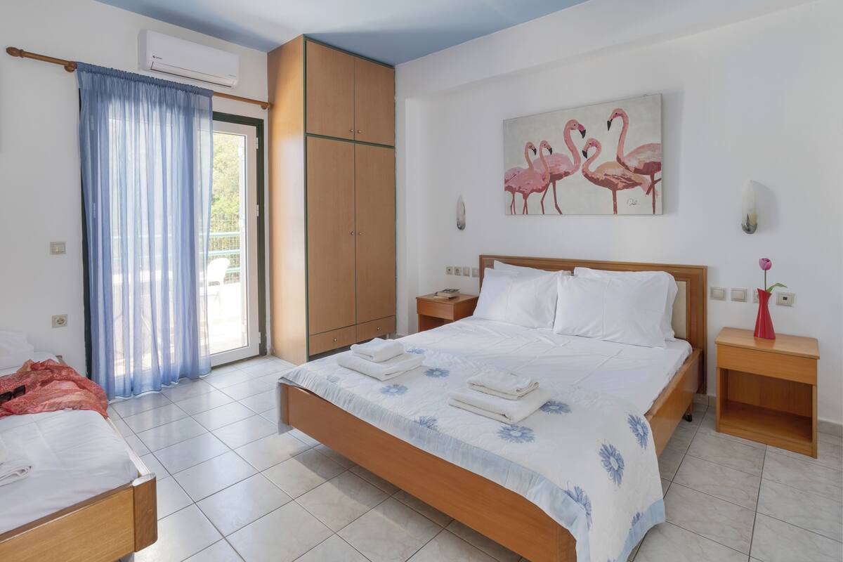 Une chambre à coucher comprenant un lit, une armoire, une table de chevet et un tableau représentant des flamants roses.
