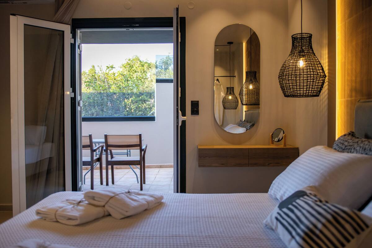 Une chambre à coucher avec un lit, une chaise, un miroir et un luminaire suspendu.