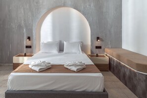 Une chambre d’hôtel moderne avec un grand lit, deux tables de chevet et un banc le long du mur.