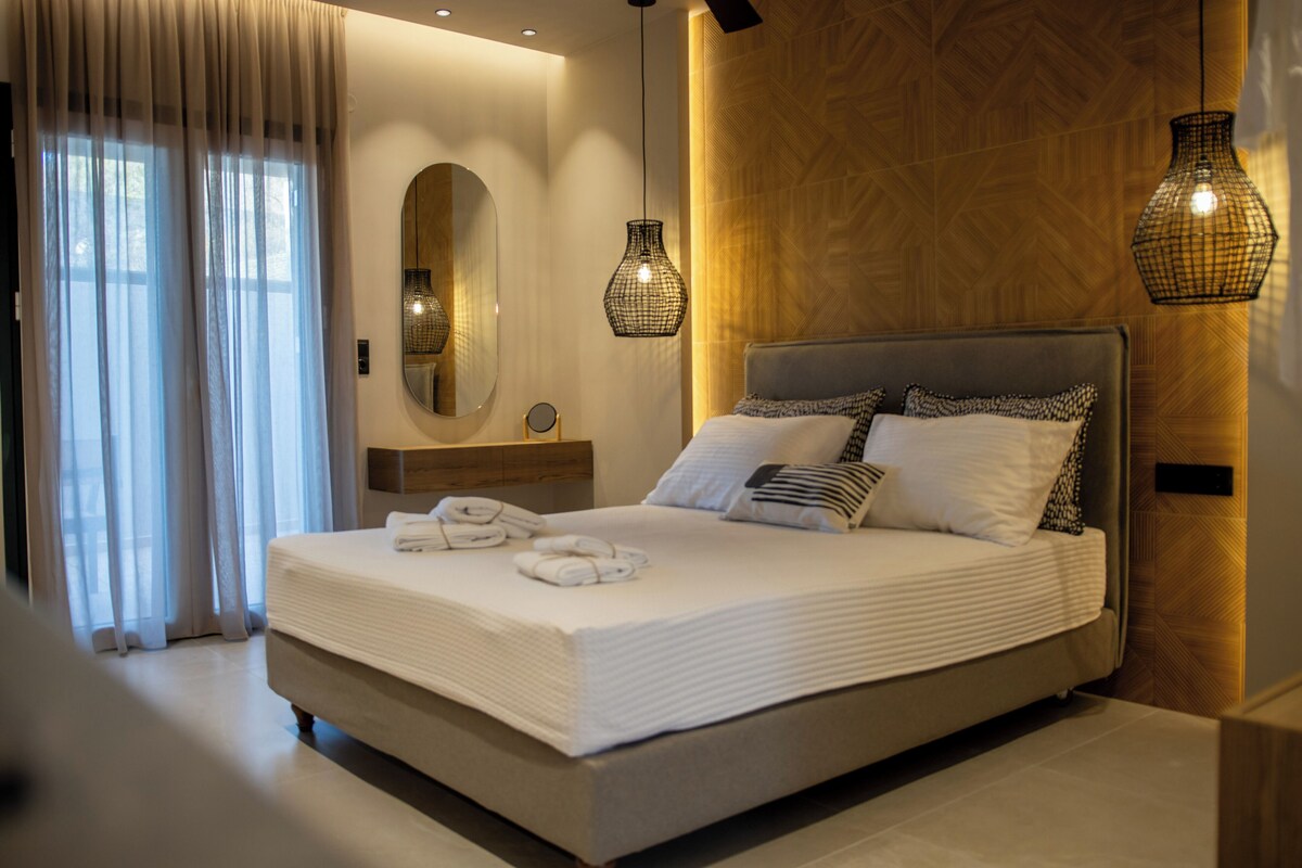 Une chambre d’hôtel moderne avec un grand lit, un miroir et deux lampes suspendues.
