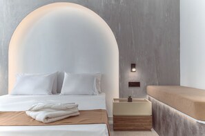 Een moderne slaapkamer met een groot bed, een nachtkastje met een lamp en een bankje.